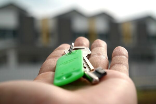 A person holding a set of keys with a green keychain