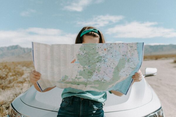 a person leaning against a car, looking at a map