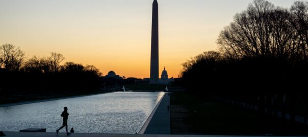 Jogger at sunset with the silhouette of the Washington Monument and the Capitol Building in the background.